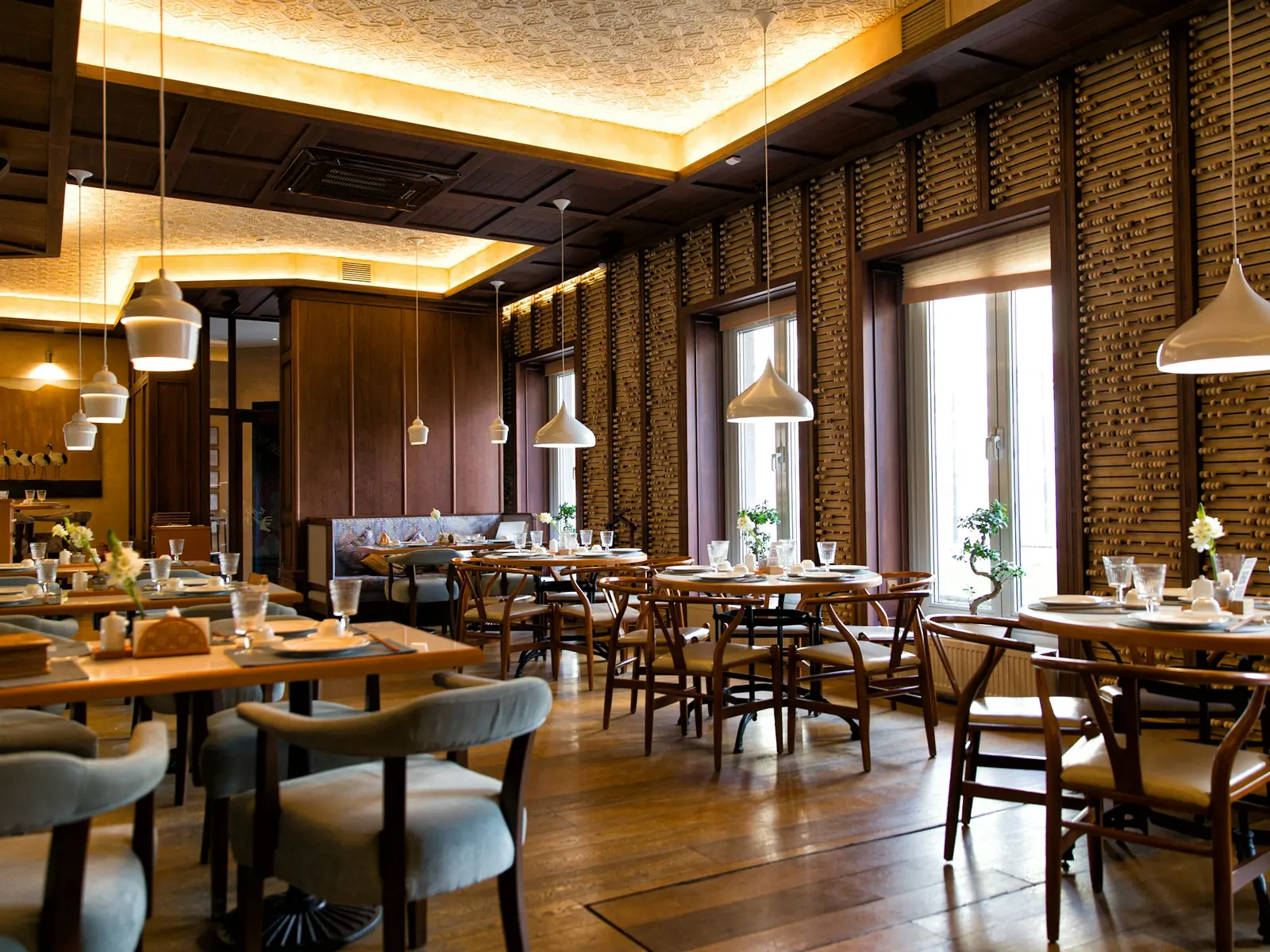 Clean restaurant dining room with set tables, chairs and a wood floor